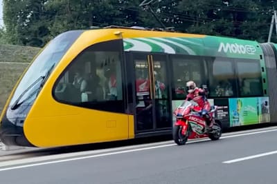 Takaaki Nakagami auf der MotoGP-Honda neben dem LRT-Zug