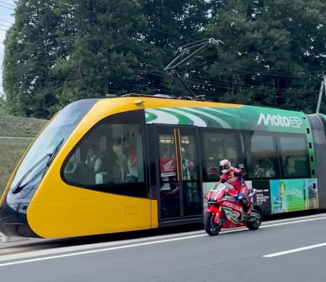 Takaaki Nakagami auf der MotoGP-Honda neben dem LRT-Zug