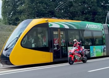 Takaaki Nakagami auf der MotoGP-Honda neben dem LRT-Zug