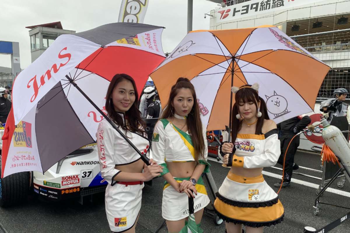 Die Damen posieren vor den Autos für die Fotografen