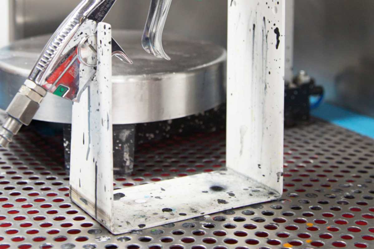 Die Farbspritzpistole, inklusive orangener Farbkleckse unten rechts