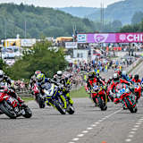 Adam McLean (56) biegt vor Gary Johnson (7) als Führender in die erste Kurve ein