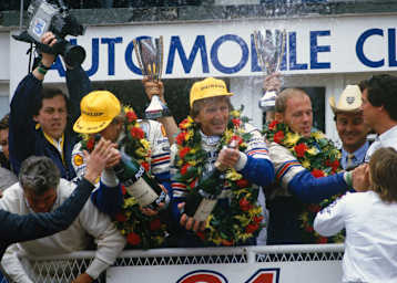 Derek Bell (Mitte mit Mütze) bei seinem Le-Mans-Sieg 1986 an der Seite von Hans-Joachim Stuck (li.) und Al Holbert