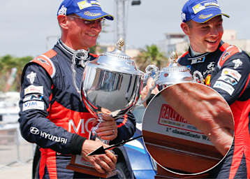 Podium der Rallye Italien. Hayden Paddon (rechts) und Beifahrer John Kennard wissen’s schon – die erhaltenen Pokale gehören eigentlich den Siegern (siehe Ausschnitt)