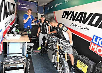 Domi Aegerter in der MotoE-Box in Assenb; links ten-Kate-Teammanager und Besucher Kervin Bos