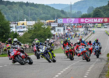 Adam McLean (56) biegt vor Gary Johnson (7) als Führender in die erste Kurve ein