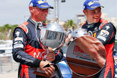 Podium der Rallye Italien. Hayden Paddon (rechts) und Beifahrer John Kennard wissen’s schon – die erhaltenen Pokale gehören eigentlich den Siegern (siehe Ausschnitt)