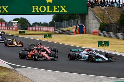 George Russel nach dem Start vor den beiden Ferrari von Carlos Sainz und Charles Leclerc