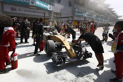 Die Renault-Mechaniker schieben den beschädigten Wagen von Magnussen weg