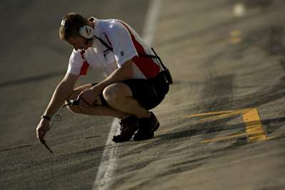 Ein Reifentechniker misst die Oberflächen-Temperatur des Asphalts