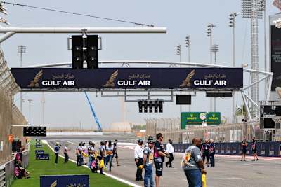 So sieht das in Bahrain aus: Normale Startampel (unter dem mittleren "Gulf Air"), Zusatzampel bei der fünften Startreihe (links oben am Querbalken), die niedrigen Leuchten unten links wegen des Halos (beim weissen F auf rotem Grund)