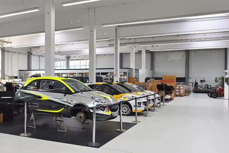 Hier sind die Rallyefahrzeuge Opel Adam zu sehen. Im Hintergrund die Kalex-Räumlichkeiten und ein paar Zweiräder