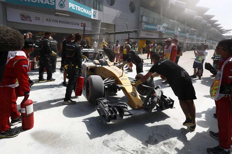 Die Renault-Mechaniker schieben den beschädigten Wagen von Magnussen weg