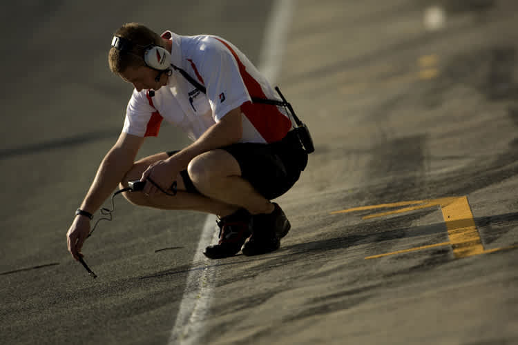 Ein Reifentechniker misst die Oberflächen-Temperatur des Asphalts